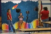 A child being photographed on the small stage in front of the coloured pencil backdrop