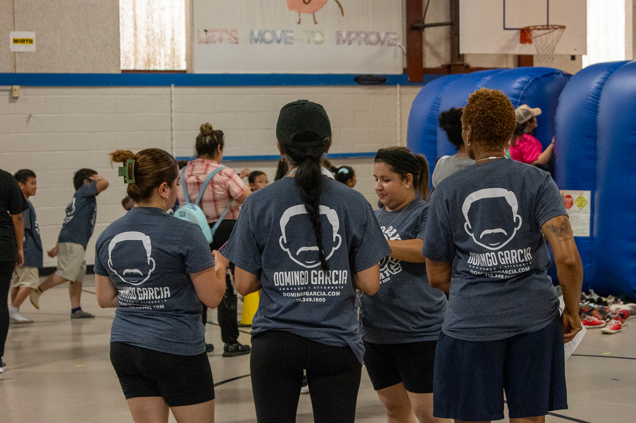 Volunteers in the firm's branded t-shirts gathered at an indoor community basketball event